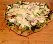 Kylie's pizza with homemade pesto, homemade ricotta, grilled chicken, red onion, green pepper, and mozzarella.